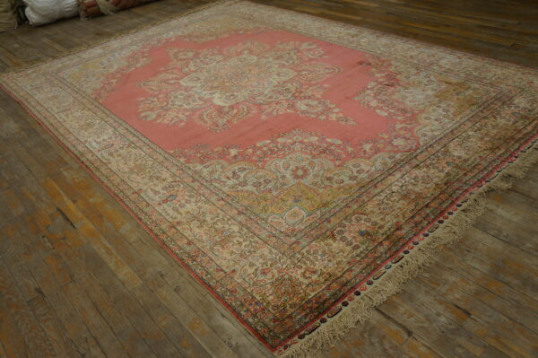 Ornate pink and cream traditional medallion rug rests on distressed dark wood plank flooring.