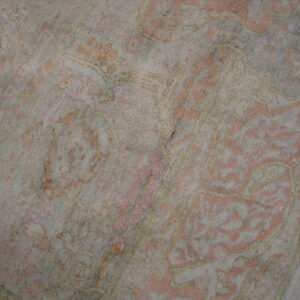 High-pile rug featuring a distressed traditional pattern in soft pink and gray on dark wood floor.