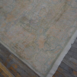 Low-pile traditional rug featuring faded blue and blush tones and white fringe on distressed wood.