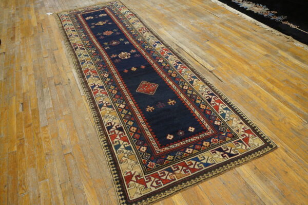 Traditional navy runner with geometric patterns in red and gold resting on golden plank flooring.