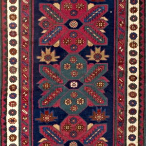 Narrow runner rug with geometric medallions in deep red, blue, and teal on a navy field.