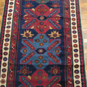 Navy, red, and teal runner with repeating geometric designs lying on polished wood flooring.