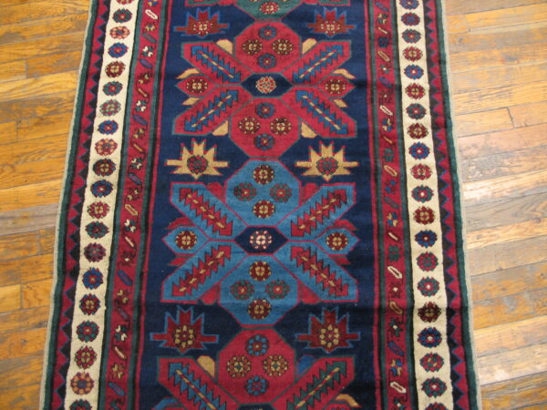 Navy, red, and teal runner with repeating geometric designs lying on polished wood flooring.