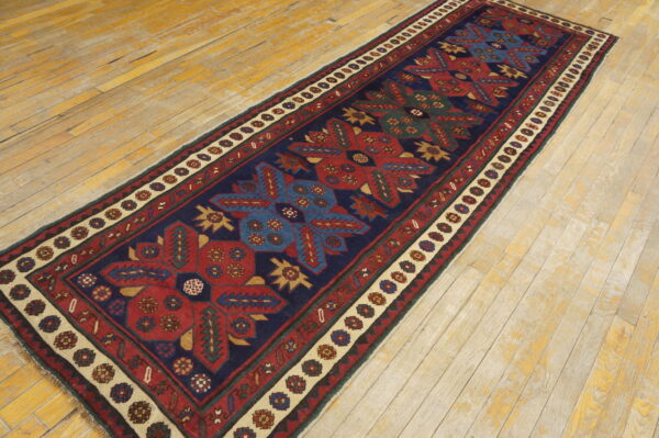 Navy, red, and blue tribal runner with a cream border is displayed on distressed wood flooring.