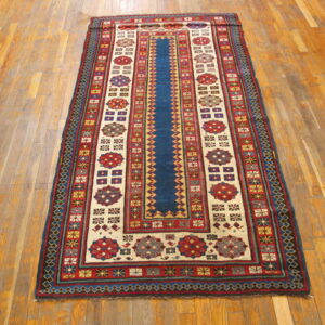 Traditional runner rug featuring a navy blue center and geometric red and cream borders on light wood flooring.