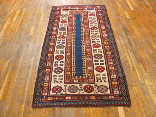 Traditional runner rug featuring a navy blue center and geometric red and cream borders on light wood flooring.