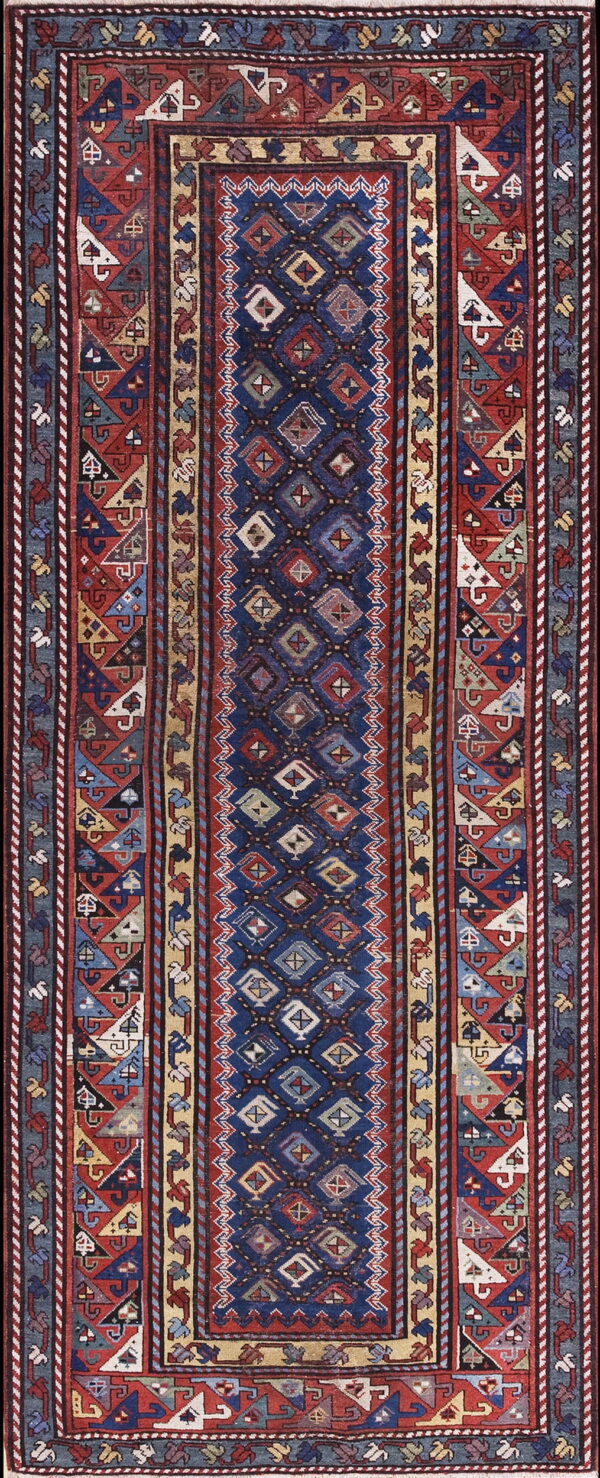 Geometric runner rug with a navy blue center panel and complex red, tan, and blue tribal borders.
