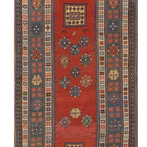 Red and blue tribal rug with geometric flowers and medallions, framed by wide patterned borders.
