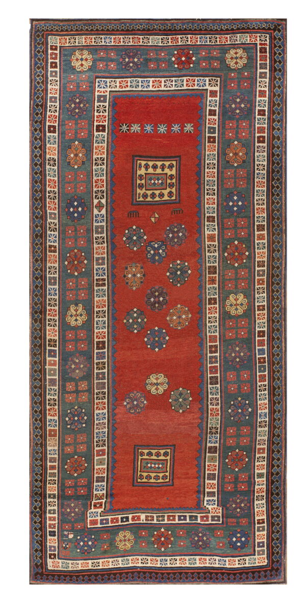 Red and blue tribal rug with geometric flowers and medallions, framed by wide patterned borders.