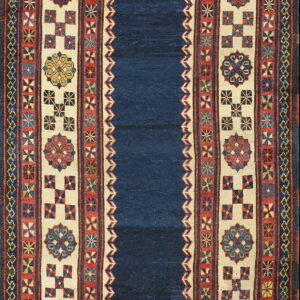 Geometric textile rug with a deep blue field and ivory borders displaying red and multicolored medallions.