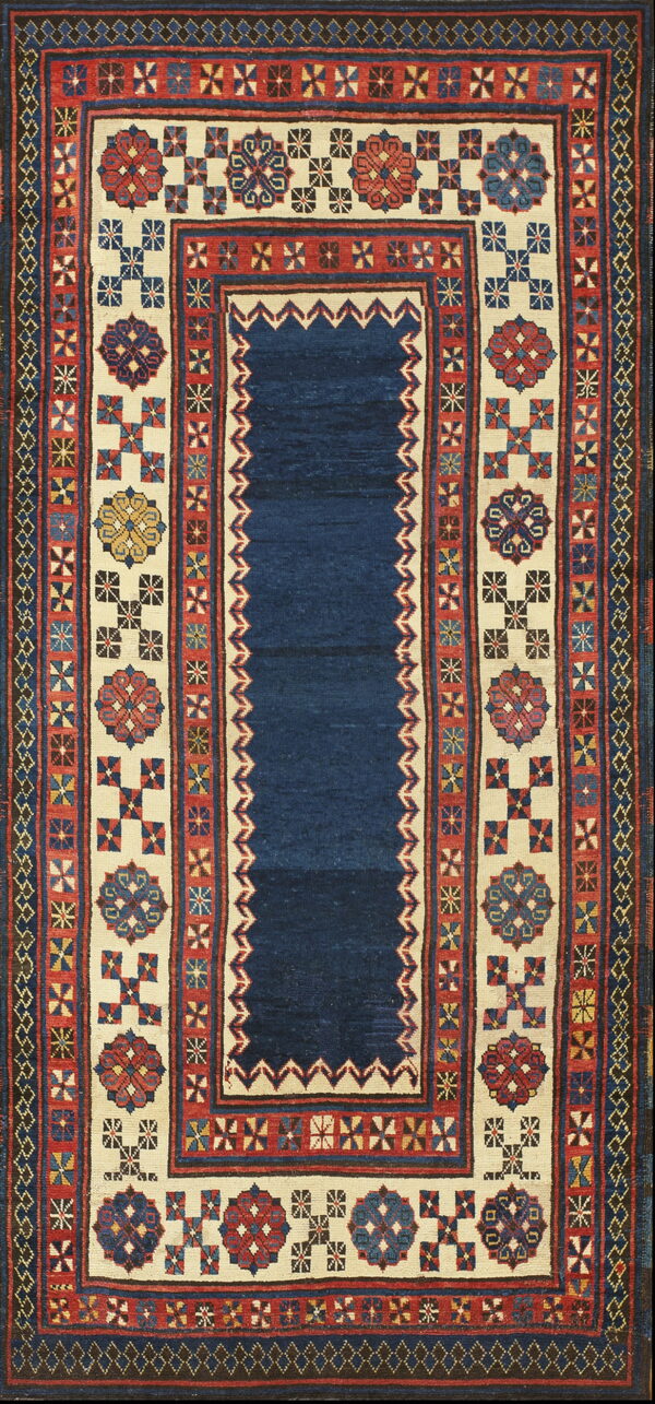 Geometric textile rug with a deep blue field and ivory borders displaying red and multicolored medallions.