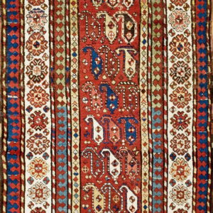 Traditional narrow rug in red, cream, blue, and brown, featuring geometric center medallions and floral borders.
