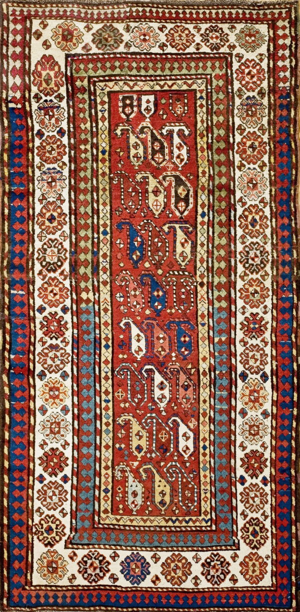 Traditional narrow rug in red, cream, blue, and brown, featuring geometric center medallions and floral borders.