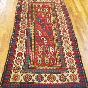 Low-pile geometric runner in red, cream, and blue with ornate borders on a polished wood floor.