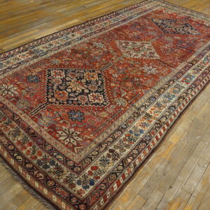Long low-pile rug featuring complex red, navy, and cream geometric designs on distressed wood floors.