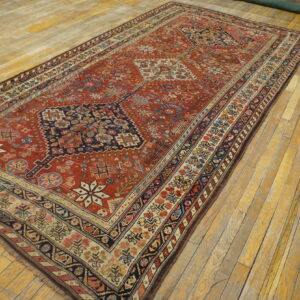 Terracotta patterned rug featuring blue, cream, and multicolor geometric borders covers worn wooden flooring.