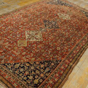 Large red and navy rug featuring an intricate all-over pattern and small medallions on distressed wood planks.