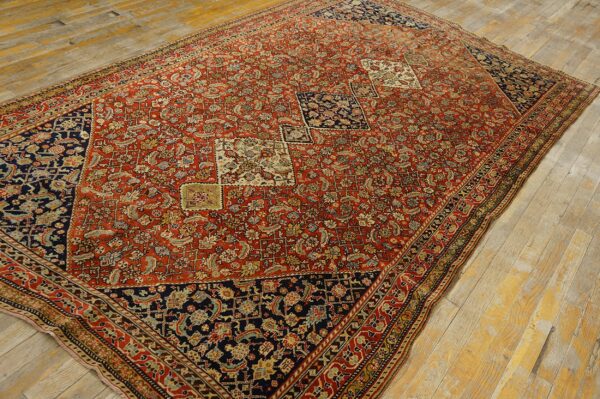 Large red and navy rug featuring an intricate all-over pattern and small medallions on distressed wood planks.