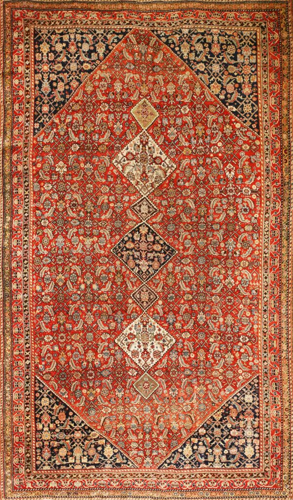 Intricate, low-pile red and navy rug featuring detailed floral motifs and connected diamond medallions.