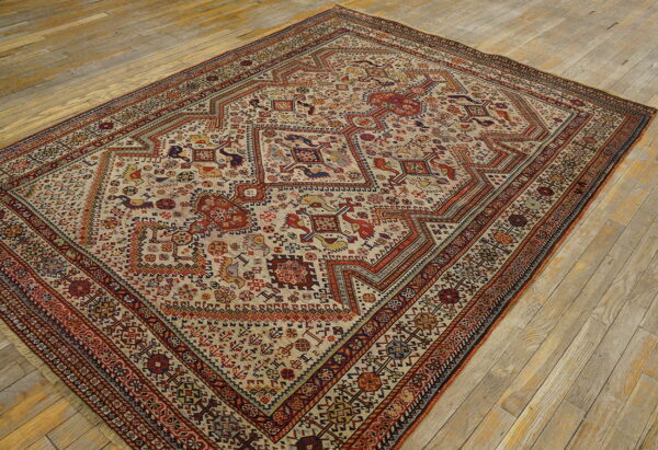 Stepped medallion rug with intricate red, blue, and yellow tribal patterns on a light tan ground over wood planks.