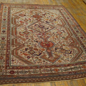 Detailed geometric rug in cream, rust, and navy blue on a worn hardwood floor.