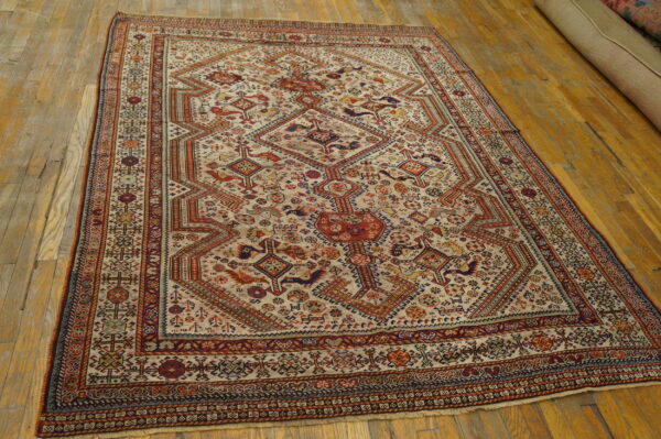 Detailed geometric rug in cream, rust, and navy blue on a worn hardwood floor.