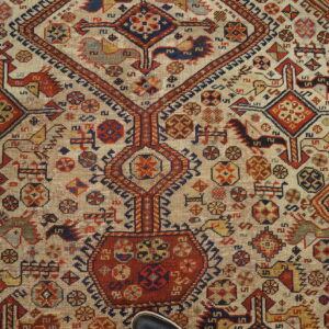 Low-pile rug with a cream field, featuring complex geometric designs in red, navy, yellow, and brown tones.