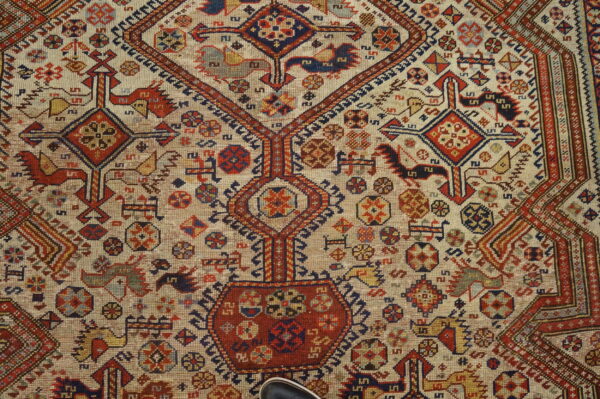 Low-pile rug with a cream field, featuring complex geometric designs in red, navy, yellow, and brown tones.