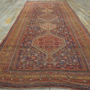 A densely patterned red and navy low-pile runner with geometric medallions covers distressed wood planks.