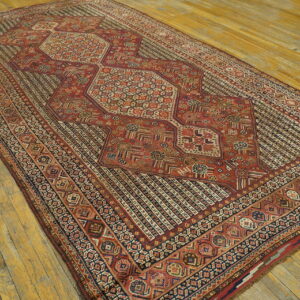 Red and navy geometric rug with a segmented central medallion lying on wide, weathered wood floors.