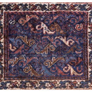 Close-up of a medium pile rug featuring a traditional design in deep blue, rust, brown, and cream.