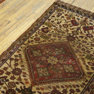 A beige and red patterned rug and a second runner lie diagonally on light colored wood flooring.