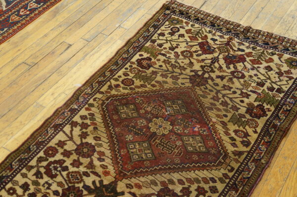 A beige and red patterned rug and a second runner lie diagonally on light colored wood flooring.