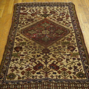 Traditional runner rug with a central red diamond design and floral motifs on light beige and wood floors.
