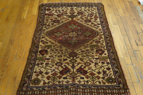 Traditional runner rug with a central red diamond design and floral motifs on light beige and wood floors.
