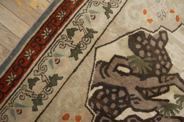 Close-up of a traditional patterned rug in beige, red, and brown on rustic, distressed wood floor.