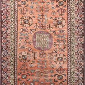 Terracotta runner rug featuring geometric tribal symbols and a central medallion in burgundy, beige, and dark brown.