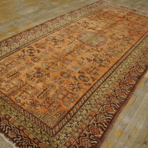 Orange and brown tribal pattern rug with a central medallion lies on distressed wooden floorboards.
