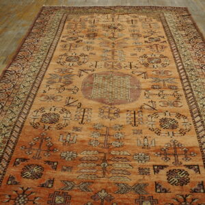 Orange runner rug with a geometric pattern sits lengthwise on worn wooden plank flooring.