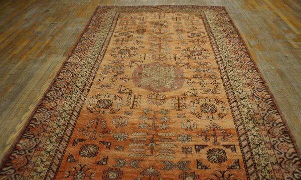 Orange runner rug with a geometric pattern sits lengthwise on worn wooden plank flooring.