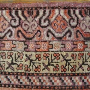 Detailed rug borders show stylized floral, geometric, and scrolling patterns in pink, orange, black, and cream.