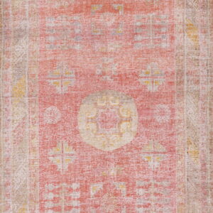 Vertical view of a distressed, low-pile rug featuring faded coral, beige, and yellow geometric patterns.