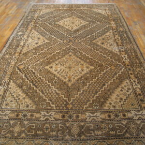 Warm brown and tan rug featuring a large central geometric diamond pattern on wood planks.