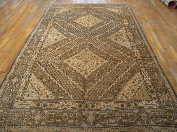 Warm brown and tan rug featuring a large central geometric diamond pattern on wood planks.