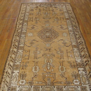 Geometric tan rug featuring dark brown tribal designs rests on narrow-plank wooden flooring.