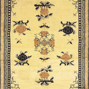 A pale yellow rug featuring stylized black and brown floral and geometric patterns with multiple key borders.