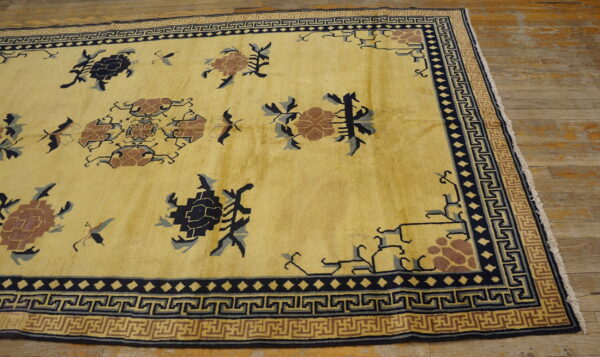Ornate yellow rug featuring navy and brown patterns and complex geometric fret borders on wood flooring.
