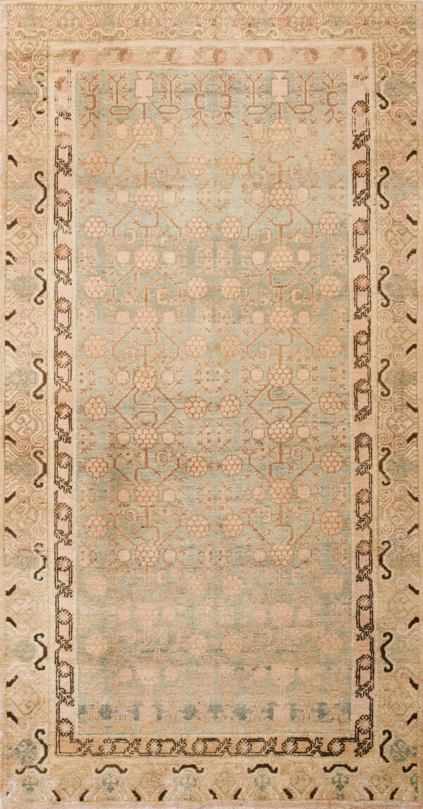 Low-pile rug with a pale blue geometric floral field and multi-banded beige and pink borders.