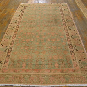 Traditional green and faded peach low-pile rug with a detailed botanical pattern on hardwood floors.