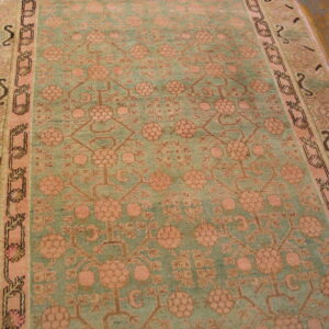 Distressed teal and blush rug with a geometric floral design shown on wide plank hardwood flooring.